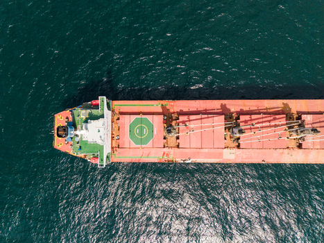 Aerial view of a large bulk carrier ship with a red deck and green helipad sailing on the dark blue waters of the Black Sea near Varna Varna Bulgaria. Aerial view of a large bulk carrier ship with a red deck and green helipad sailing on the dark blue waters of the Black Sea near Varna Varna Bulgaria.