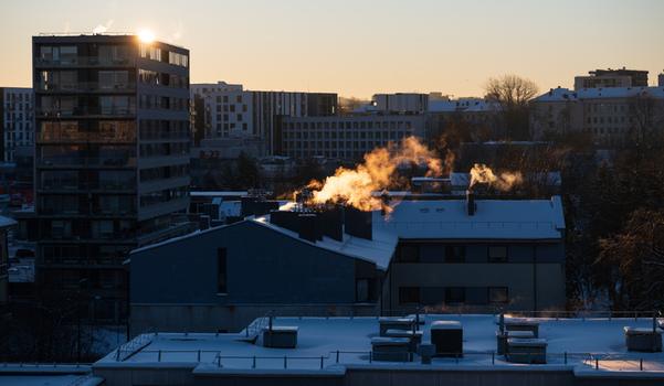 View of snow covered rooftops with smoke rising from chimneys during a golden sunset in the city of Vilnius Vilnius County Lithuania. View of snow covered rooftops with smoke rising from chimneys during a golden sunset in the city of Vilnius Vilnius County Lithuania.
