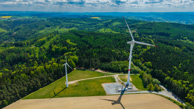 Aerial view of Zipotin wind turbines standing on a grassy hill surrounded by dense green forests and rolling hills under a cloudy sky Gruna Pardubicky kraj Czechia. Aerial view of Zipotin wind turbines standing on a grassy hill surrounded by dense green forests and rolling hills under a cloudy sky Gruna Pardubicky kraj Czechia.