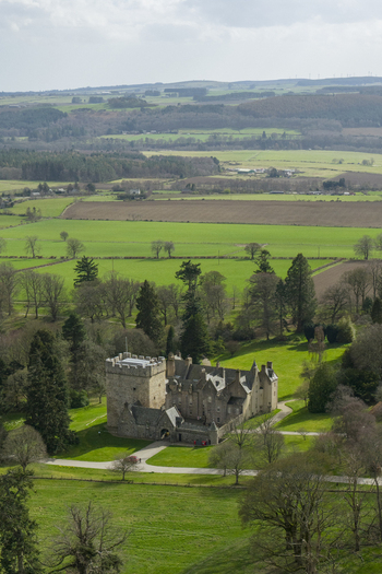 Aerial view of Drum Castle with its historic stone tower and surrounding green estate grounds in Drumoak Scotland United Kingdom.