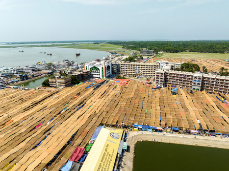 Aerial view of expansive golden mats spread across the landscape contrasting with the blue waters and the grand mosque Charmonai Barisal Division Bangladesh. Aerial view of expansive golden mats spread across the landscape contrasting with the blue waters and the grand mosque Charmonai Barisal Division Bangladesh.