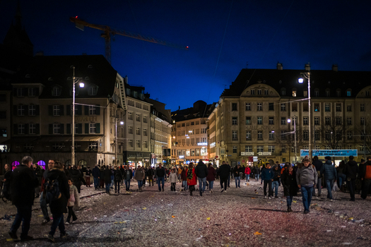 Basel Switzerland 10 March 2025 View of a crowded square shimmering under the night sky littered with confetti surrounded by the dark silhouettes of grand buildings. Basel Switzerland 10 March 2025 View of a crowded square shimmering under the night sky littered with confetti surrounded by the dark silhouettes of grand buildings.