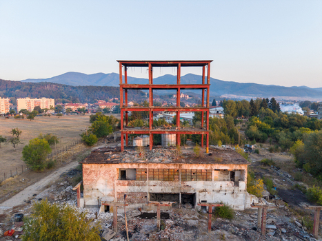 Aerial view of an abandoned industrial building with a prominent red steel frame structure surrounded by rural landscape and mountains in Velingrad Pazardzhik Bulgaria. Aerial view of an abandoned industrial building with a prominent red steel frame structure surrounded by rural landscape and mountains in Velingrad Pazardzhik Bulgaria.