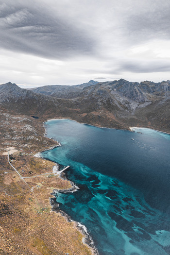 Aerial view of the rugged coastline and turquoise waters of a fjord in Senja Troms Norway.