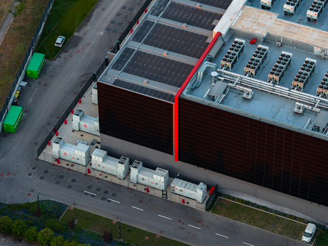 Aerial view of a modern datacenter facility featuring rooftop cooling units solar panels and external power generators in Settecamini Lazio Italy.
