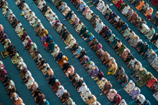 Dhaka Bangladesh 19 June 2026 Aerial view of rows of men praying in a mosque with people kneeling on a blue carpet in an organized formation.