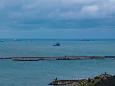 Aerial view of cargo ships anchored in the bay behind a long concrete breakwater under a cloudy sky in Taichung Taichung City Taiwan. Aerial view of cargo ships anchored in the bay behind a long concrete breakwater under a cloudy sky in Taichung Taichung City Taiwan.