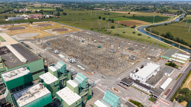 Aerial view of the Tavazzano power station featuring a large electrical substation industrial buildings and surrounding green fields with a canal in Tavazzano con Villavesco Lombardy Italy.