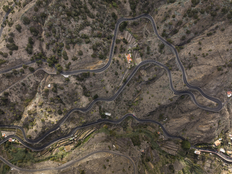 Aerial view of a winding mountain road with sharp curves cutting through the rugged rocky landscape of La Gomera in Santa Cruz de Tenerife Canary Islands Spain.