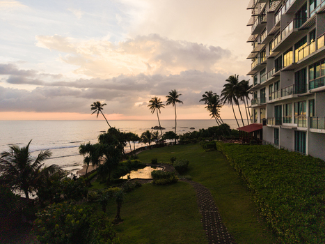 Aerial view of Gintota beach featuring palm trees a green lawn and a modern resort building at sunset Galle Southern Province Sri Lanka. Aerial view of Gintota beach featuring palm trees a green lawn and a modern resort building at sunset Galle Southern Province Sri Lanka.