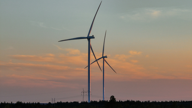 Aerial view of Metsalamminkangas Tuulipuisto wind turbines standing tall against a soft golden hour sky above a dense forest landscape Siikalatva Pohjois Pohjanmaa Finland. Aerial view of Metsalamminkangas Tuulipuisto wind turbines standing tall against a soft golden hour sky above a dense forest landscape Siikalatva Pohjois Pohjanmaa Finland.