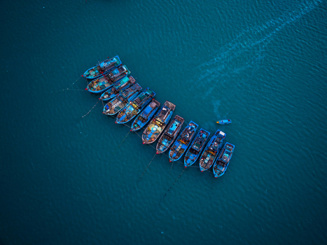 Aerial view of a line of blue fishing boats moored in calm deep blue water in Vietnam. Aerial view of a line of blue fishing boats moored in calm deep blue water in Vietnam.