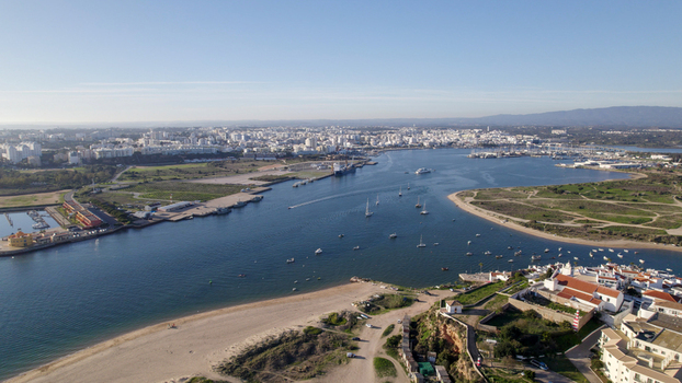 Aerial view of the coastal town of Ferragudo featuring the Arade River estuary small boats sandy beaches and historic architecture in Ferragudo Faro District Portugal.