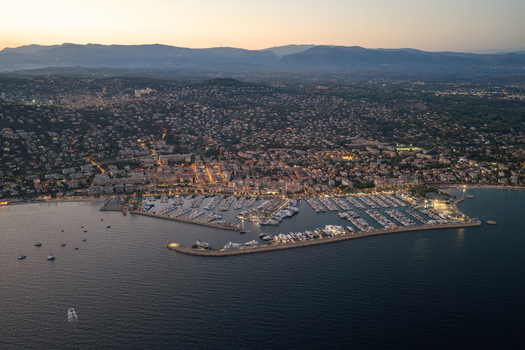 Aerial view of the harbor in Antibes filled with yachts at dusk with the illuminated city stretching along the coastline in Antibes Provence Alpes Cote d Azur France. Aerial view of the harbor in Antibes filled with yachts at dusk with the illuminated city stretching along the coastline in Antibes Provence Alpes Cote d Azur France.