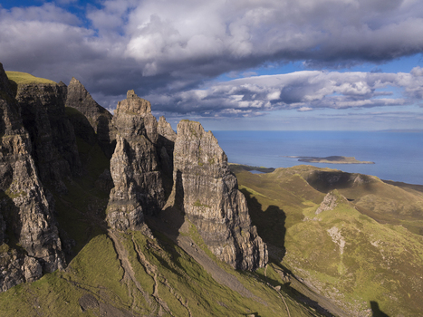 Aerial view of the Old Man of Storr a dramatic rock formation on the Isle of Skye with rugged cliffs grassy slopes and the sea in the background in Scotland United Kingdom. Aerial view of the Old Man of Storr a dramatic rock formation on the Isle of Skye with rugged cliffs grassy slopes and the sea in the background in Scotland United Kingdom.