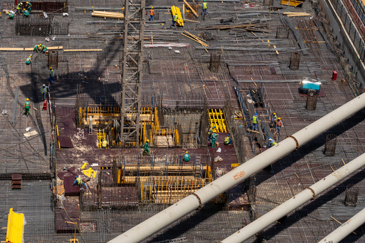 Aerial view of construction workers active on a rebar foundation with large pipes and crane shadows in Dubai Dubai United Arab Emirates. Aerial view of construction workers active on a rebar foundation with large pipes and crane shadows in Dubai Dubai United Arab Emirates.