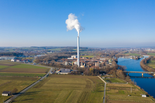 Aerial view of the Liapor GmbH Co KG industrial facility with a tall chimney emitting white smoke near a river and bridge in Hallerndorf Bayern Germany. Aerial view of the Liapor GmbH Co KG industrial facility with a tall chimney emitting white smoke near a river and bridge in Hallerndorf Bayern Germany.