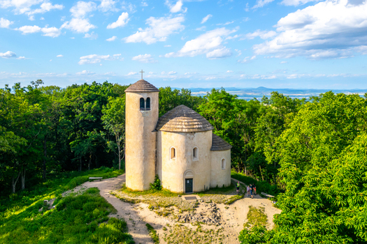 Aerial view of the historic Rotunda of Saint George on Rip Mountain surrounded by lush green forest under a bright blue sky in Mnetes Usti nad Labem Region Czechia. Aerial view of the historic Rotunda of Saint George on Rip Mountain surrounded by lush green forest under a bright blue sky in Mnetes Usti nad Labem Region Czechia.