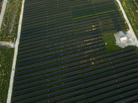 Aerial view of a large solar panel farm with rows of photovoltaic modules installed on green fields under soft evening light in Augusta Sicily Italy. Aerial view of a large solar panel farm with rows of photovoltaic modules installed on green fields under soft evening light in Augusta Sicily Italy.