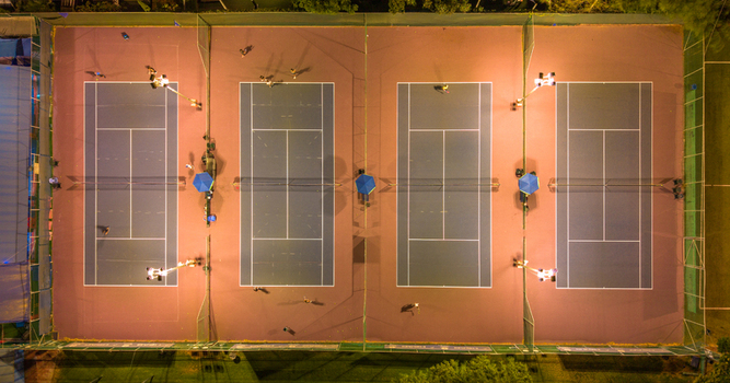 Aerial view of multiple tennis courts illuminated at night with players on the courts in Tel Aviv Yafo Tel Aviv District Israel. Aerial view of multiple tennis courts illuminated at night with players on the courts in Tel Aviv Yafo Tel Aviv District Israel.