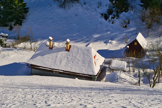 View of snow laden roofs of quaint buildings stand nestled amidst the pristine white landscape reflecting the crisp winter sunlight Moce Banska Bystrica Region Slovakia.