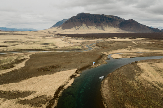 Aerial view of a winding river flowing through the vast barren tundra landscape of Borgarbyggd Iceland. Aerial view of a winding river flowing through the vast barren tundra landscape of Borgarbyggd Iceland.