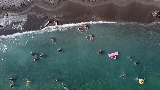 Aerial view of people swimming in turquoise water by a dark sand beach Italy. Aerial view of people swimming in turquoise water by a dark sand beach Italy.