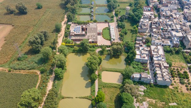 Aerial view of a fishing farm with multiple ponds surrounding agricultural fields and nearby residential buildings in Punjab Pakistan. Aerial view of a fishing farm with multiple ponds surrounding agricultural fields and nearby residential buildings in Punjab Pakistan.