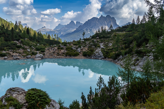 View of the turquoise waters of Lake Sorapis surrounded by rocky mountain peaks and pine trees in the Dolomites Cortina d Ampezzo Veneto Italy.