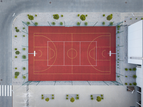 Aerial view of a red basketball court with yellow markings surrounded by a green fence and small shrubs in Wieliczka Lesser Poland Voivode Poland.