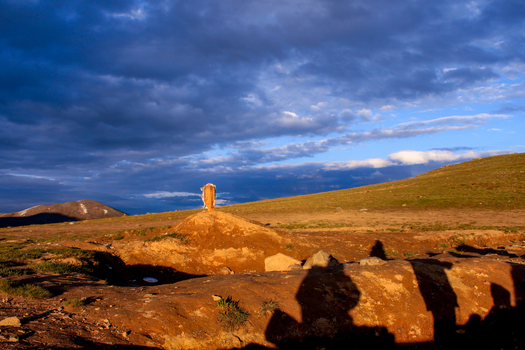 View of Sheosar Lake with a wooden marker on a small mound surrounded by rolling grassy hills under a dramatic sunset sky in Skardu Pakistan. View of Sheosar Lake with a wooden marker on a small mound surrounded by rolling grassy hills under a dramatic sunset sky in Skardu Pakistan.