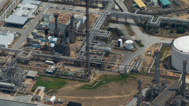 Aerial view of an industrial refinery complex with intricate piping systems storage tanks and tall chimneys in Tambon Pa Yup Nai Chang Wat Rayong Thailand. Aerial view of an industrial refinery complex with intricate piping systems storage tanks and tall chimneys in Tambon Pa Yup Nai Chang Wat Rayong Thailand.