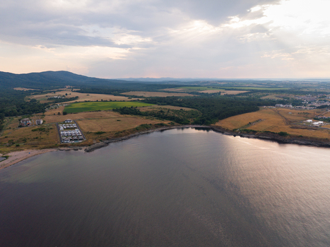 Aerial view of the coastline and bay near Tsarevo featuring rolling hills agricultural fields and a small residential area under a cloudy sky in Tsarevo Burgas Bulgaria. Aerial view of the coastline and bay near Tsarevo featuring rolling hills agricultural fields and a small residential area under a cloudy sky in Tsarevo Burgas Bulgaria.
