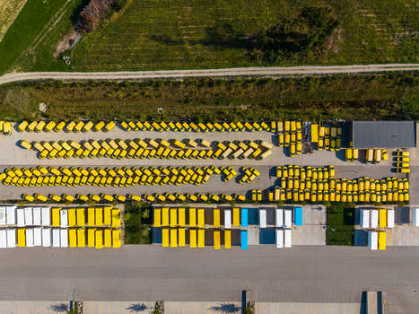 Aerial view of the Logistikzentrum Allhaming featuring rows of yellow delivery vans and white trailers parked in a large asphalt yard in Allhaming Oberosterreich Austria. Aerial view of the Logistikzentrum Allhaming featuring rows of yellow delivery vans and white trailers parked in a large asphalt yard in Allhaming Oberosterreich Austria.