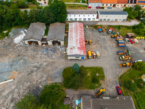 Aerial view of an industrial yard featuring construction machinery parked trucks and warehouse buildings with metal roofs in Zebrak Central Bohemian Region Czechia. Aerial view of an industrial yard featuring construction machinery parked trucks and warehouse buildings with metal roofs in Zebrak Central Bohemian Region Czechia.