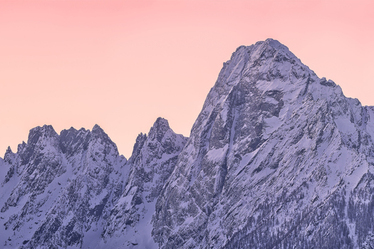 Aerial view of Valchiavenna mountain peaks covered in snow under a soft pink sunset sky in Lombardy Italy. Aerial view of Valchiavenna mountain peaks covered in snow under a soft pink sunset sky in Lombardy Italy.