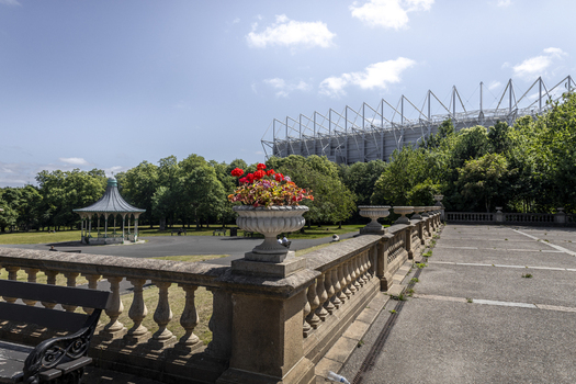 View of Leazes Park with a stone balustrade a decorative urn with red flowers a bandstand and the St. James Park stadium in the background in Newcastle upon Tyne England United Kingdom. View of Leazes Park with a stone balustrade a decorative urn with red flowers a bandstand and the St. James Park stadium in the background in Newcastle upon Tyne England United Kingdom.