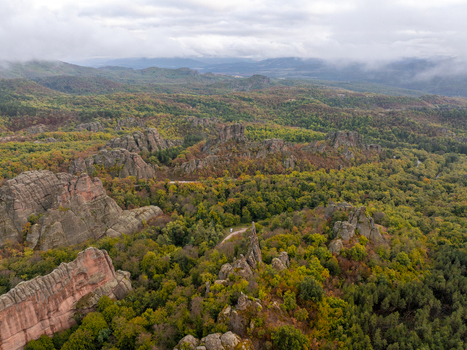 Aerial view of the unique sandstone and conglomerate rock formations of the Belogradchik Rocks surrounded by a dense autumn forest under a cloudy sky in Belogradchik Vidin Bulgaria. Aerial view of the unique sandstone and conglomerate rock formations of the Belogradchik Rocks surrounded by a dense autumn forest under a cloudy sky in Belogradchik Vidin Bulgaria.