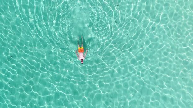 Aerial view of a man floating in turquoise water Maldives.