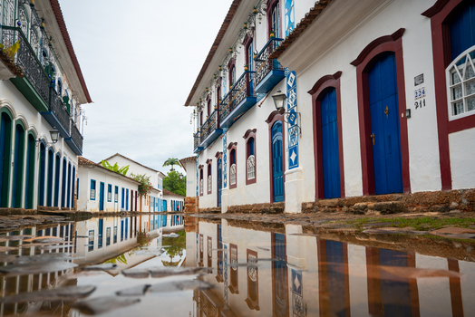 View of historic colonial buildings with colorful doors and windows reflected in a puddle on a cobblestone street Paraty State of Rio de Janeiro Brazil. View of historic colonial buildings with colorful doors and windows reflected in a puddle on a cobblestone street Paraty State of Rio de Janeiro Brazil.