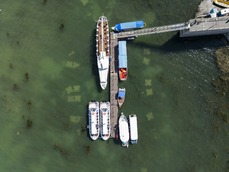 Aerial view of various boats moored at the wooden pier on the clear green waters of Lake Shkodra in Shiroka Shkoder County Albania. Aerial view of various boats moored at the wooden pier on the clear green waters of Lake Shkodra in Shiroka Shkoder County Albania.