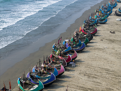 Cox s Bazar Bangladesh 10 March 2026 Aerial view of a long row of colorful traditional moon boats parked on the sandy shore of the beach with people and ocean waves crashing nearby. Cox s Bazar Bangladesh 10 March 2026 Aerial view of a long row of colorful traditional moon boats parked on the sandy shore of the beach with people and ocean waves crashing nearby.