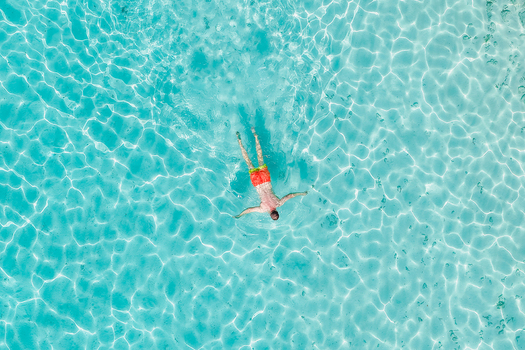 Aerial view of a person swimming in crystal clear turquoise water with sunlight reflecting on the surface in Innafinolhu Haa Alif Atoll Maldives. Aerial view of a person swimming in crystal clear turquoise water with sunlight reflecting on the surface in Innafinolhu Haa Alif Atoll Maldives.