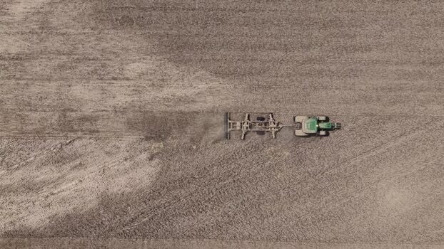Aerial view of a tractor plowing a dry field in Portugal. Aerial view of a tractor plowing a dry field in Portugal.