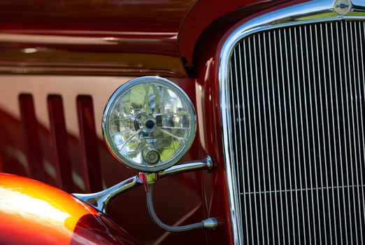 View of a vintage red car featuring a polished chrome grille and a round headlight in Langley British Columbia Canada. View of a vintage red car featuring a polished chrome grille and a round headlight in Langley British Columbia Canada.