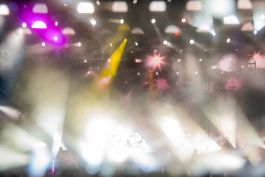 View of a concert stage illuminated by bright colorful spotlights and atmospheric smoke with silhouettes of the audience in the foreground in Switzerland.