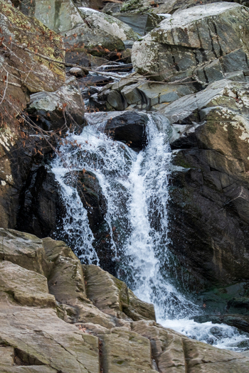 View of cascading water plunges down a rocky cliff face creating a dynamic contrast between the smooth water and rough rock Scott s Run Virginia United States. View of cascading water plunges down a rocky cliff face creating a dynamic contrast between the smooth water and rough rock Scott s Run Virginia United States.