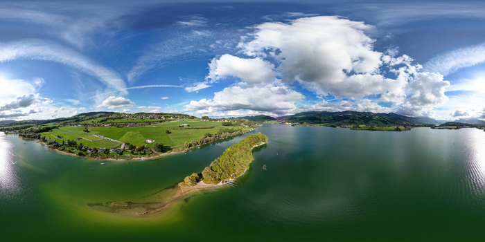 Aerial view of Lake Gruyere and the Ile d Ogoz surrounded by turquoise water and lush green hills under a cloudy blue sky Pont en Ogoz Fribourg Switzerland. Aerial view of Lake Gruyere and the Ile d Ogoz surrounded by turquoise water and lush green hills under a cloudy blue sky Pont en Ogoz Fribourg Switzerland.