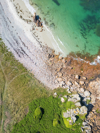 Aerial view of Plage de Port Blanc featuring turquoise water a pebbly beach and large granite boulders along the coast in Penvenan Bretagne France. Aerial view of Plage de Port Blanc featuring turquoise water a pebbly beach and large granite boulders along the coast in Penvenan Bretagne France.