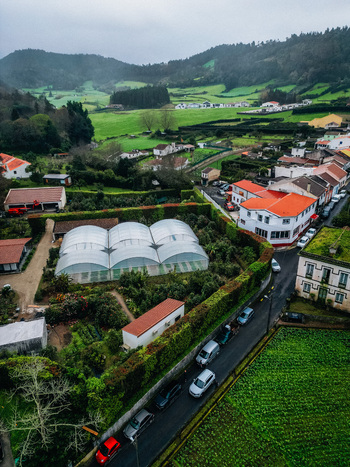 Aerial view of a quaint village nestled amidst verdant hills where white buildings with terracotta roofs contrast with the lush green landscape Furnas Azores Portugal.